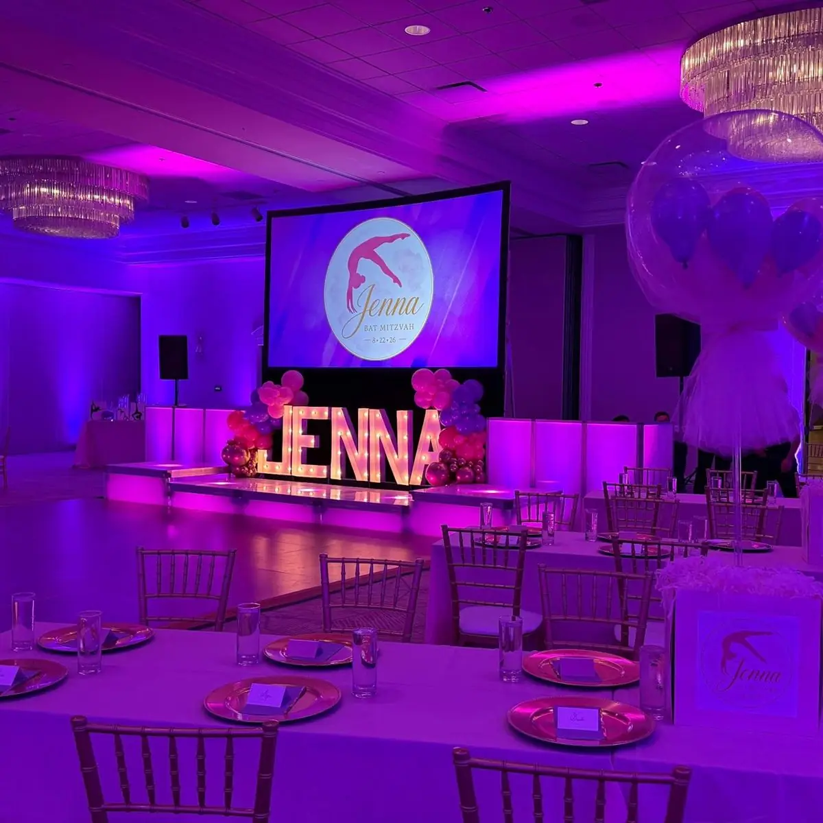 After: the same ballroom transformed for Jenna’s Bat Mitzvah, with colored lighting, balloons, a lit stage and a dance floor