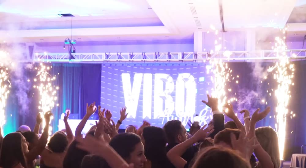 Corporate party crowd with cold sparks firing beside a VIBO LED wall