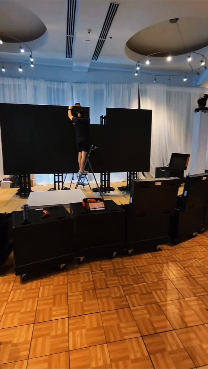 Production crew setting up an LED video wall in an event space