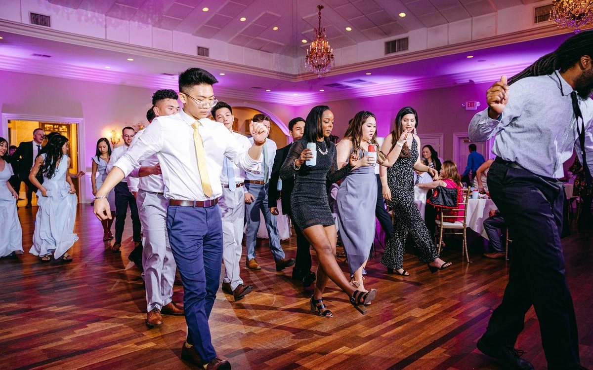 A full dance floor under purple ATG uplighting and the chandeliers at the Magnolia Room
