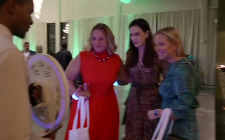 Guests in a ballroom using a roaming photo booth