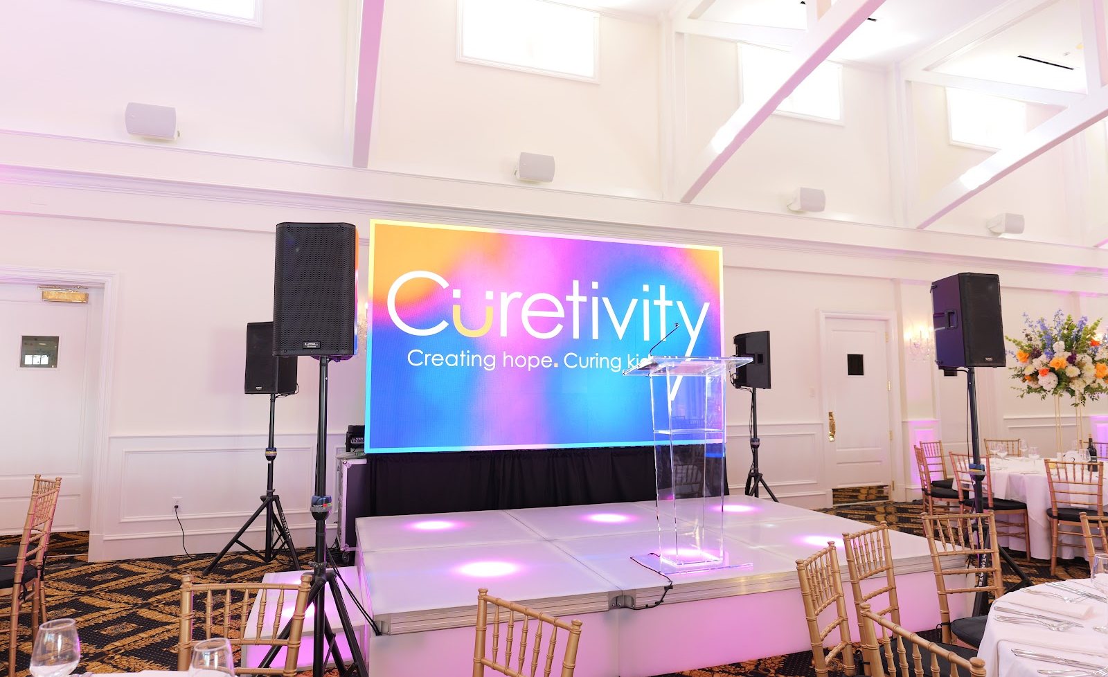 Corporate stage with LED video wall, lit risers and sound for Curetivity