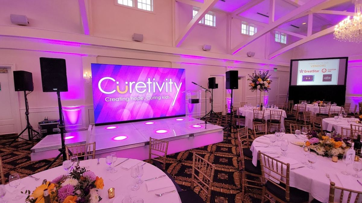 LED video wall and speakers set up for a corporate event in a ballroom