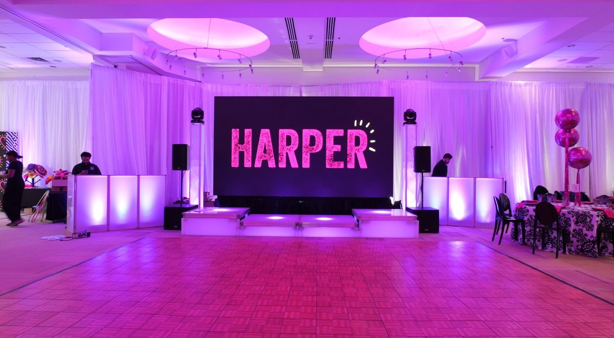 A ballroom wrapped in white drape washed with pink and lavender ATG uplighting