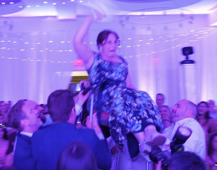 The hora: a guest lifted high in a chair over a packed dance floor
